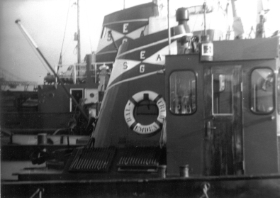 Schleppschiffe helfen  dem Schiff RHEINSTEIN BREMEN im Jahr 1967 beim Auslaufen aus dem Emder Hafen