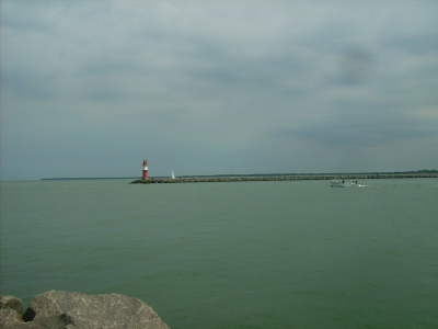 Farbfoto: Blick von der Westmole zur Ostmole. Der auf diesem Foto nicht sichtbare Leuchtturm auf der Westmole ist grün, der auf diesem Foto sichtbare Leuchtturm auf der Ostmole ist rot. In Warnemünde im Juni 2009. Fotograf: Bernd Paepcke.